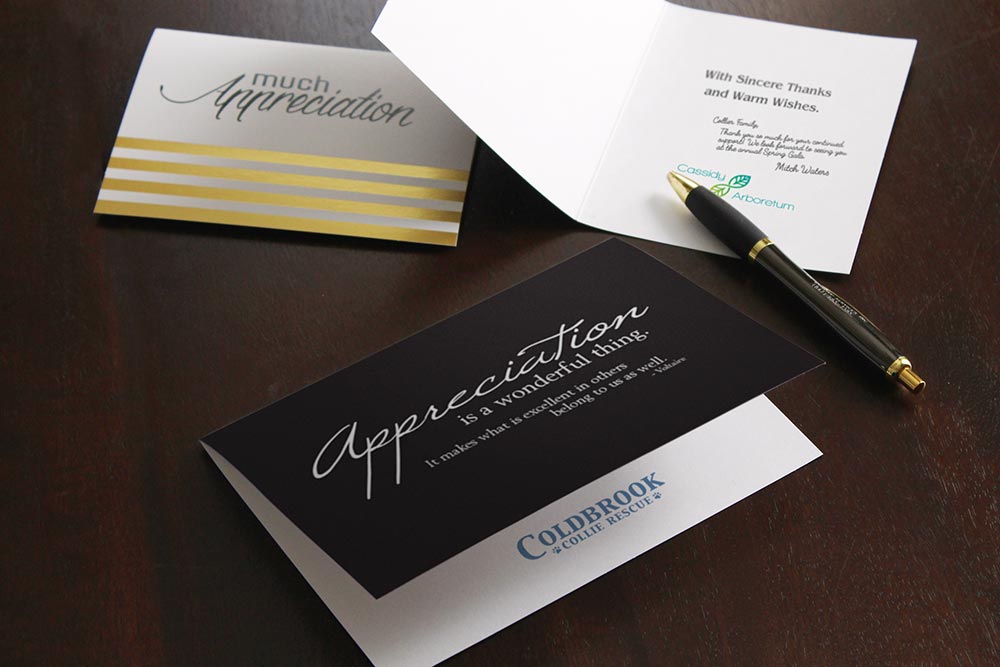 A collection of thank you note cards on a desk, each with a company logo printed inside the card.