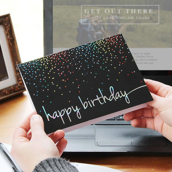 Someone holds a birthday card with colorful foil confetti