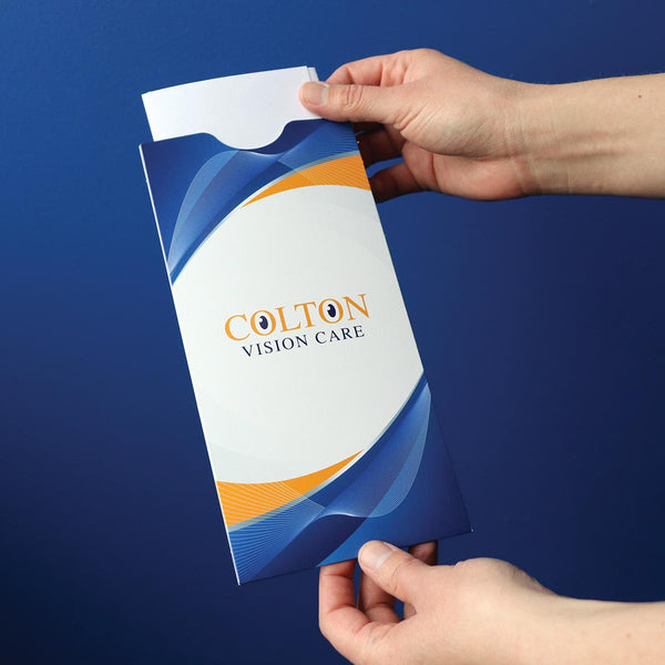 Someone pulls paperwork out of a document sleeve printed with a vision care center's branding.