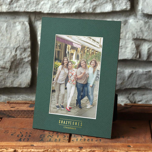 Vertical dark green frame with gold foil creamery logo imprint.