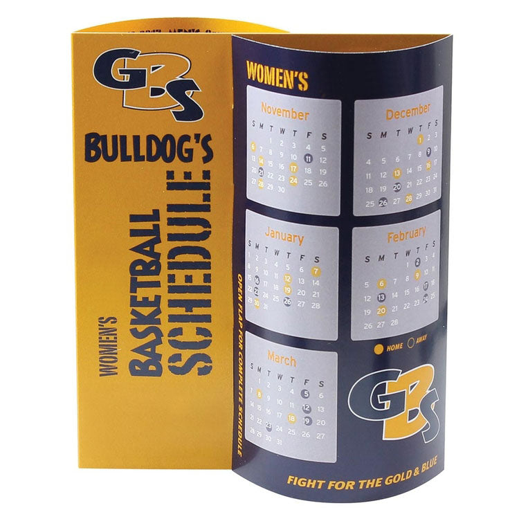 Blue and orange table tent with pop-out curved sections that have a basketball game schedule print on them for a women's school team.