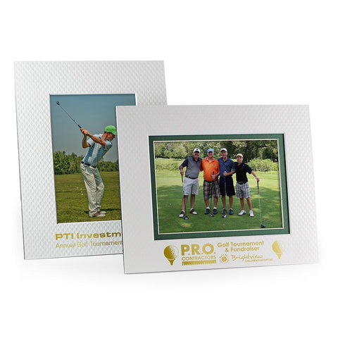 Two golf ball picture frames with gold foil event logos stamped on the frame border beneath the photos