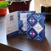 Hotel room key card holder stands upright on a wooden desk with plants in the background.