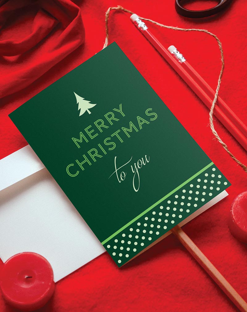 Green Christmas card with simple text and polka dot design. Card reads, Merry Christmas to you, with an evergreen tree silhouette above the text.