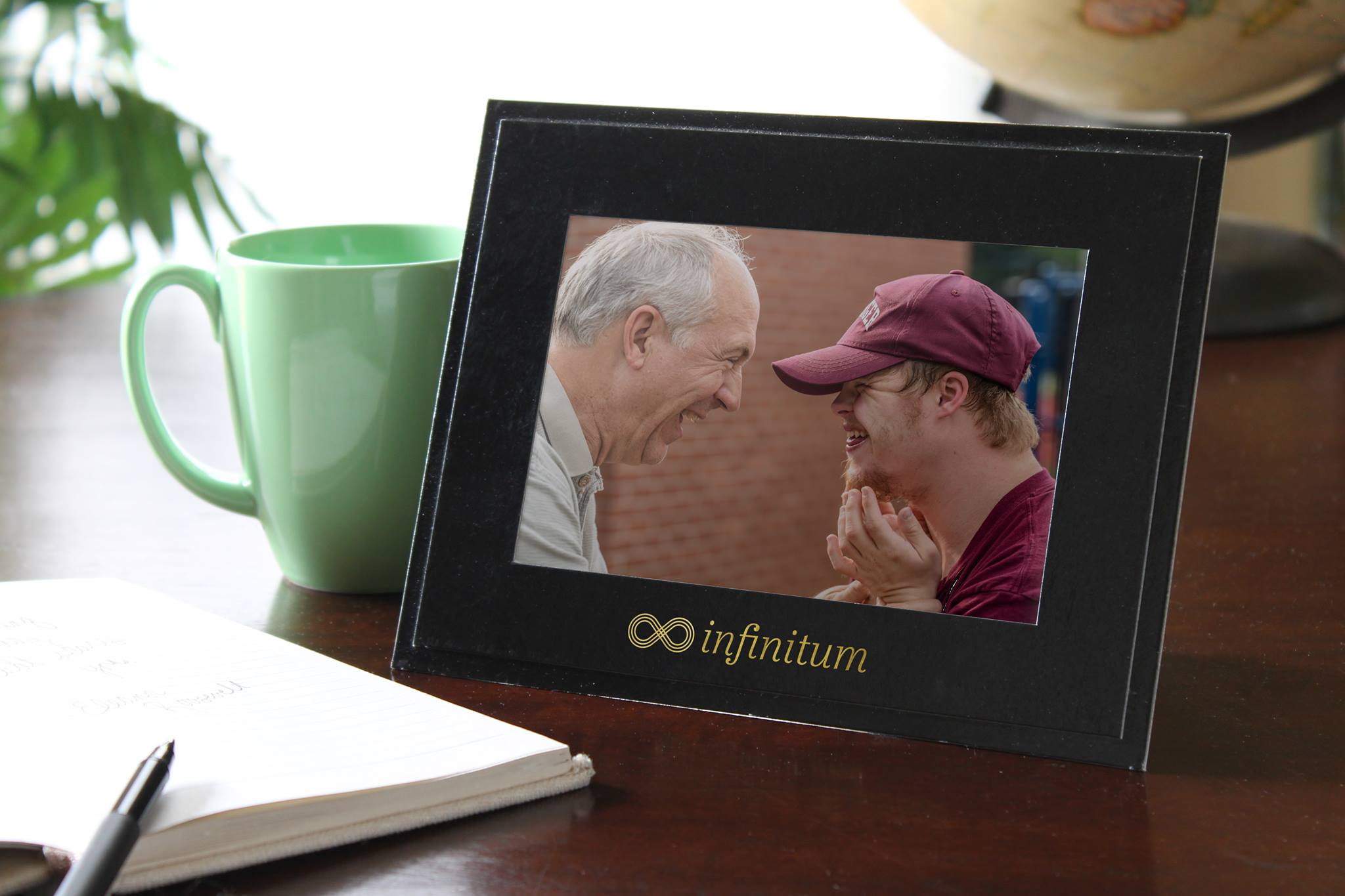 Black cardboard picture frame with a gold foil company logo imprinted on the window frame border