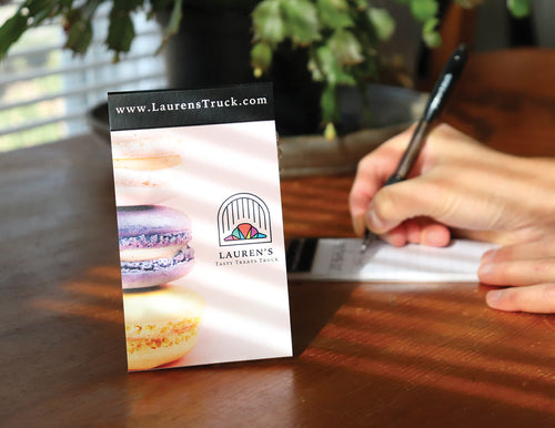 Writing notes in a budget pocket jotter with branding.