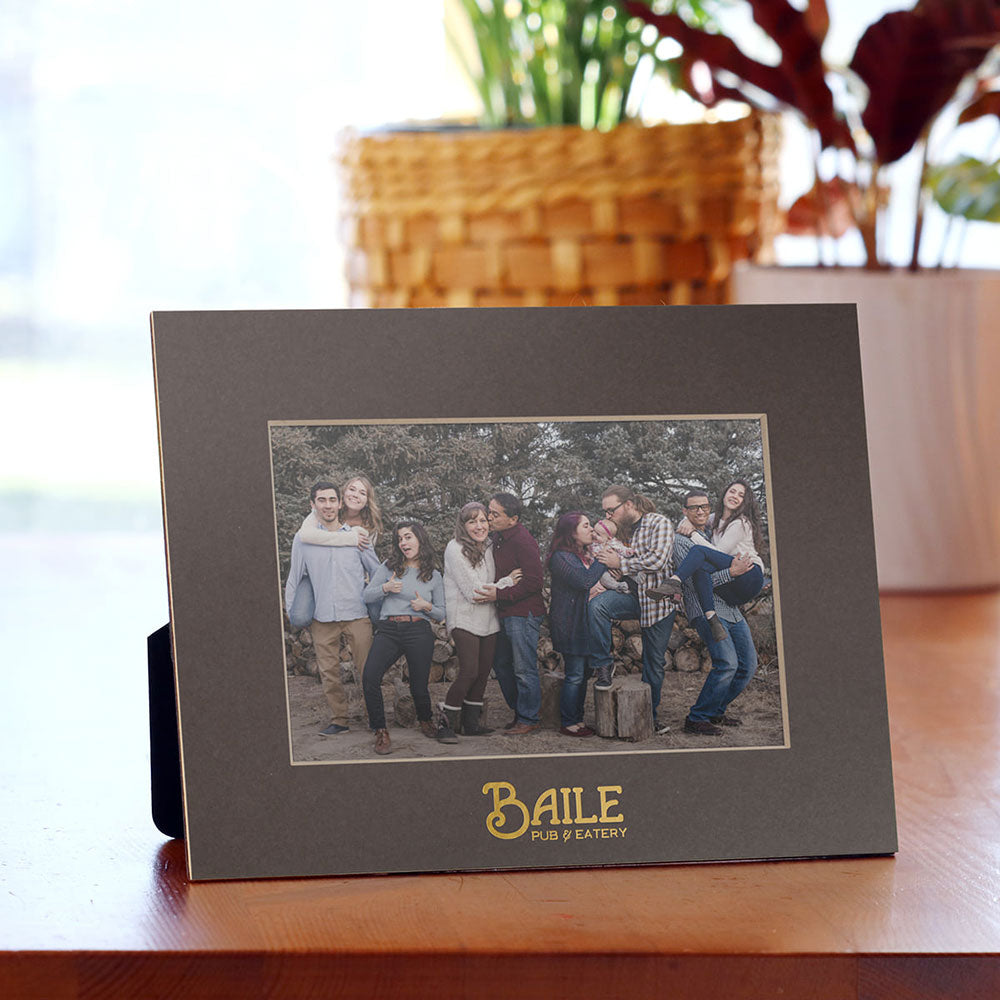 Personalized gray cardboard frame with gold foil logo imprint.