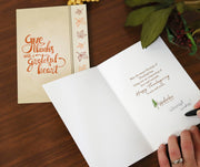 Someone writes a message in the Thanksgiving card.