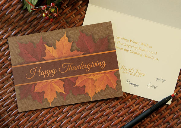 Thanksgiving leaves card lies on a woven basket surface. Front. of card lies on an open card that has a sentiment and company logo stamped inside the card.